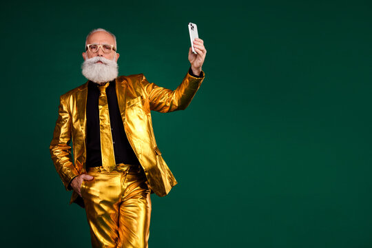 Charismatic elderly man in golden suit celebrating with style against green background