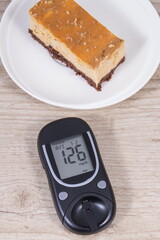 Glucometer and portion of cheesecake. Measuring and checking sugar level during diabetes