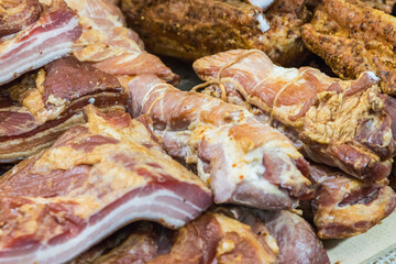 Fresh prepared smoked hams with spices in wicker basket on market stall