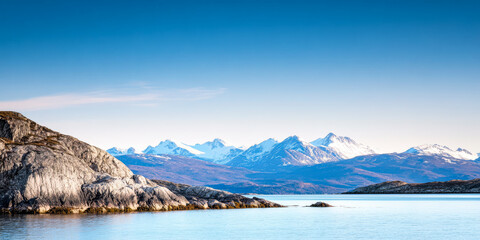 Obraz premium Beautiful snowy mountain landscape reflected in calm water beneath a clear blue sky
