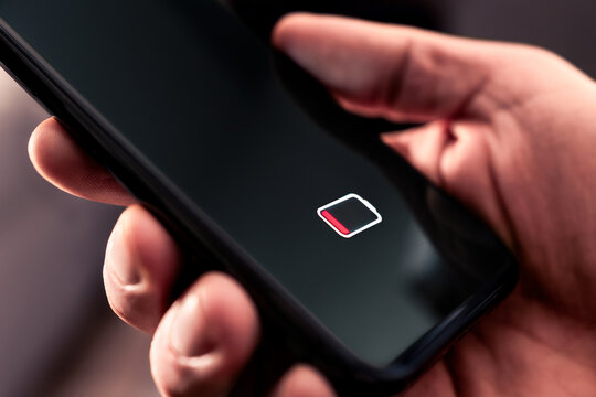 Phone battery with low charge. Cellphone with no power. Energy drain. Empty load and dead smartphone. Mobile recharge life icon symbol on screen. Man holding device in hand. Bad broken technology.