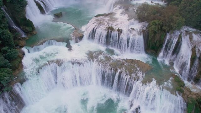 Majestic Ban Gioc Waterfall flowing amidst tropical forest during the sunset at Vietnam