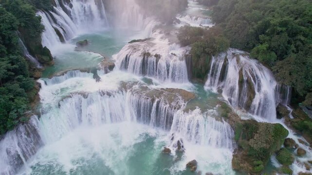 Majestic Ban Gioc Waterfall flowing amidst tropical forest during the sunset at Vietnam