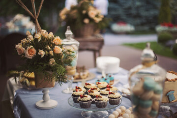Candy bar at a party. Bouquet of yellow roses on a table with different handmade desserts. Candy bar at a party. 