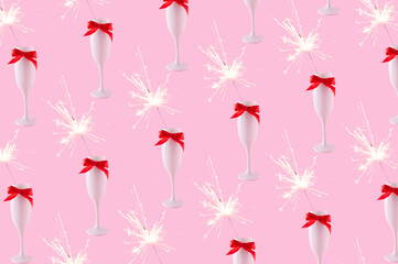 A champagne glass with red bow and sparkler on a pastel pink background. Celebration event concept.