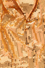 Glamorous golden metallic glowing sequins textile with pink reflection background. Christmas holiday or New Year party concept. Abstract luxury glowing textured background.