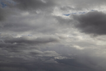 Gray sky with gray clouds and streaks of white light, overcast weather, November sky, heavenly background, celestial landscape.
