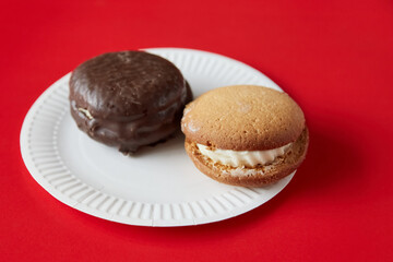 Chocolate pie and pumpkin pie on a white disposable plate against a red background, traditional desserts
