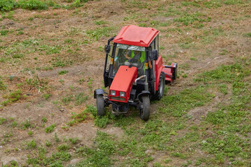 The tractor with a mower neatly trims the grass in the field.