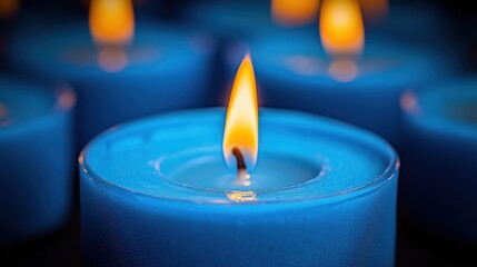 Blue candle with a yellow flame is lit. The blue candle is surrounded by other blue candles