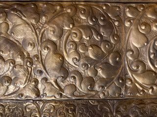 A gold leaf design on a piece of metal