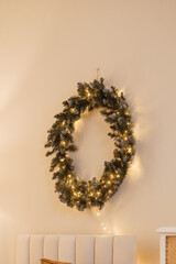 A large Christmas wreath on a bright wall in the New Year's bedroom interior. Background for New Year wallpapers and postcards.