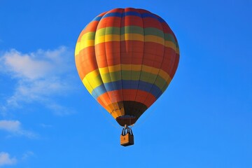 Obraz premium A colorful hot air balloon ascending into a bright blue sky, symbolizing freedom, creativity, and the achievement of new heights.