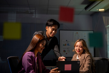 Asian businesspeople having corporate meeting using laptop in office at night