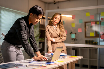Asian businesspeople working late using laptop computer in office at night