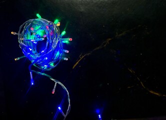 skein with multicolored christmas lights on dark marble background blinking with shades as background christmas mood authentic top view