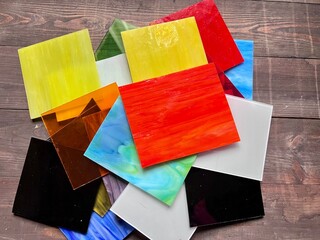 Working with colored glass for stained glass samples for creativity square colored pieces of glass on the table as a background © MariaKitsune
