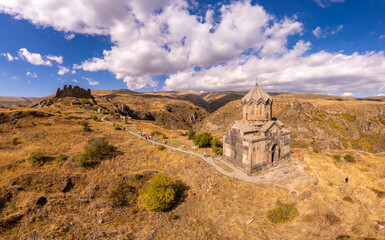 Fototapeta premium Aerial drone view of famous Vahramashen Church of the 11th century, located near destroyed Amberd fortress in sunny summer day. Cliff with Arkashian River deep in canyon. Aragatsotn region, Armenia