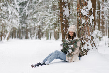 Young woman is sitting in the snow with bouquet of flowers in her lap