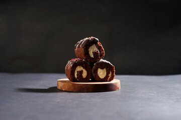 Chocolate roll cake with fresh cream in wooden plate isolated on dark background. chocolate swiss roll cake.