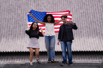 Diverse group of friends proudly holding an American flag outdoors, symbolizing unity and patriotism. Their smiles and casual poses embody freedom, friendship, and the spirit of togetherness.