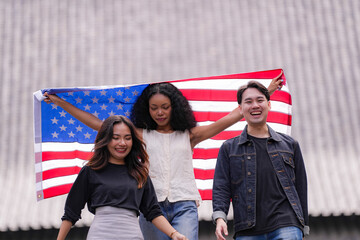 Diverse group of friends proudly holding an American flag outdoors, symbolizing unity and patriotism. Their smiles and casual poses embody freedom, friendship, and the spirit of togetherness.