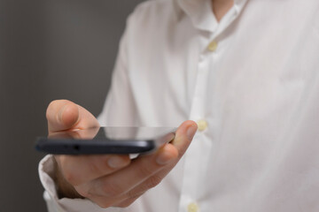 Closeup of a man using mobile smart phone with blank screen.