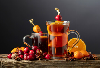 Winter drinks with spices, cranberries, and citrus fruits on a dark background.