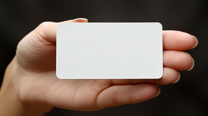 Obraz premium A hand holding a blank white card against a dark background for creative design and branding purposes. Generative AI