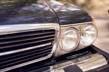 Closeup of vintage cars headlight and chrome bumper, showcasing classic automotive design details