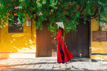 Young Vietnam woman wearing Ao Dai culture traditional walking on local street at Hoi an, Vietnam.