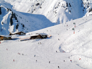 Winter ski slopes of the track on which skiers and snowboarders descend. A view from afar. Hotel buildings are also visible. Winter sports and recreation