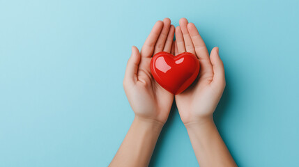 Fototapeta premium pair of hands gently cradles shiny red heart against blue background, symbolizing love and care. This evokes warmth and affection