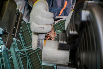 close up below A factory worker operates heavy machinery, focusing intently as he adjusts mechanical components. the industrial environment and the technical expertise required for the task.