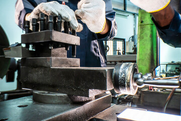 Two focused industrial technicians work together operating heavy machinery in a workshop. The image of teamwork, precision, and technical expertise in an engineering and manufacturing industry
