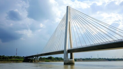 Fototapeta premium Modern cable-stayed bridge over a river with cloudy sky.