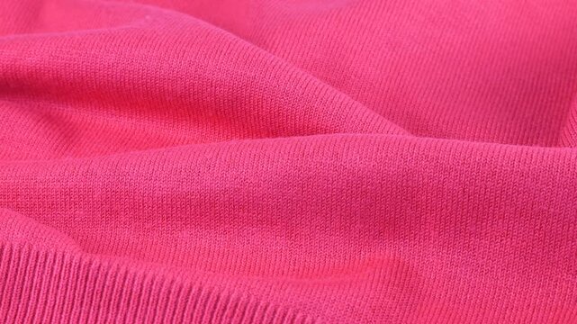 Pink color cotton jersey taffy shade. The textile background laid in folds rotates on the display case. Background on the theme of fashion, design, natural fabrics.