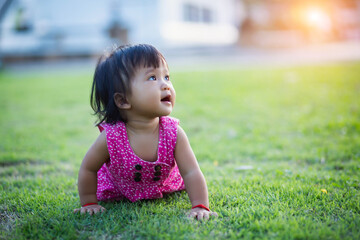 Baby girl walking outdoors dressed in pink stripped dress. Happy kid. Happy childhood.