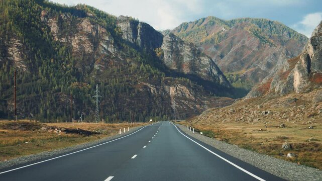 Driving on empty asphalt road in mountain valley. Delivery and cargo transportation. Travel to national parks. Straight highway goes to horizon. Electric poles in parallel to road. View in vehicle