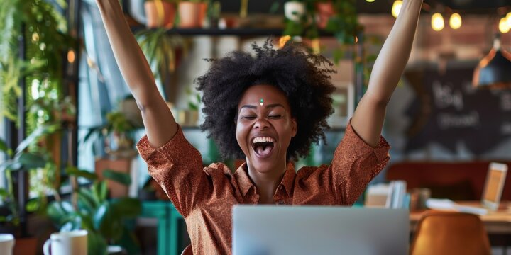 Joyful businesswoman in the office reading great news about her job promotion on her laptop, celebrating her success in the workplace
