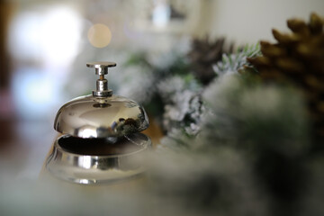 Ringing reception bell on desk of guesthouse, hotel at christmas time. Color shining garland on...