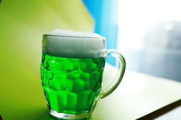 Saint Patrick's Day holiday. National Irish holiday. Green beer. Hand with a mug of emerald beer in a bar.