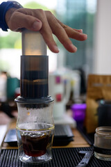 Brewing coffee with an aeropress in a cozy cafe setting alternative coffee brewing method Hands-on aeropress and glass cup scales manual grinder