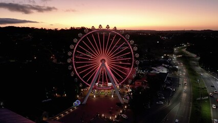 Illuminated Ferris Wheel At Canela In Rio Grande Do Sul Brazil. Colorful Ferris Wheel. Illuminated City. Sunset Landscape. Illuminated Ferris Wheel At Canela In Rio Grande Do Sul Brazil. 