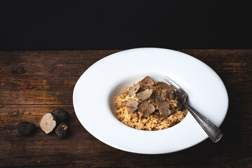 Black truffle risotto recipe. Autumn creamy consistency risotto in stylish white dish on the dark...