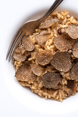 Black truffle risotto recipe. Autumn creamy consistency risotto in stylish white dish on the white background. Autumn gourmet cuisine of Piedmont, Northern Italy, France, Spain, close up