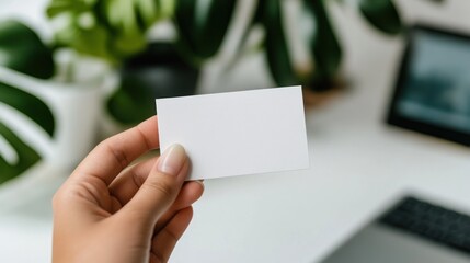 Obraz premium A hand is prominently displaying a blank business card against a softly blurred office setting