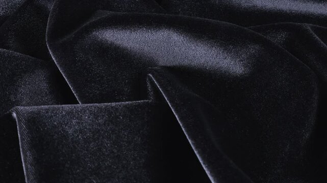 A luxurious velvet in a black color graphite shade. Textile background on theme design, fashion, tailoring and accessories. Beautiful folds of textured fabric on a rotating showcase. Top view.