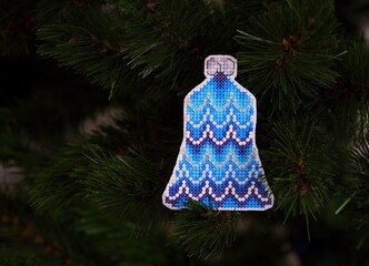 Blue bell cross stitched Christmas ornament on Christmas tree.