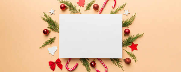 Flat lay Christmas composition. square Paper blank, pine tree branches, christmas decorations on Colored background. Top view, copy space for text